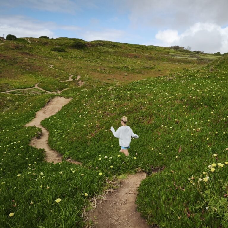 Person walking along a narrow coastal trail on a steep cliffside in Cascais. Person walking along a narrow coastal trail on a steep cliffside in Cascais.