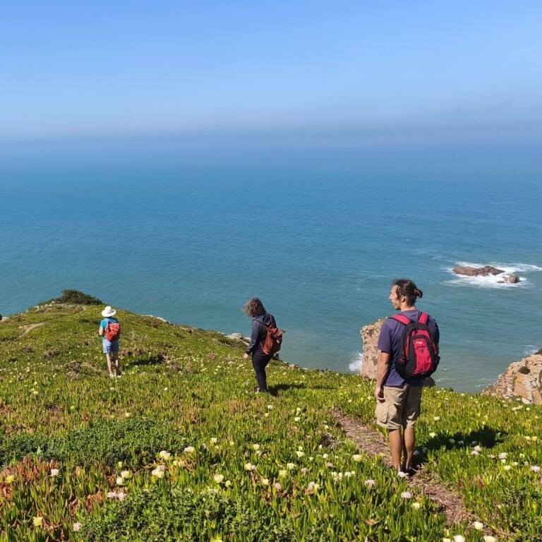 Adventurer navigating a rocky coastal path with a view of the ocean in Cascais.