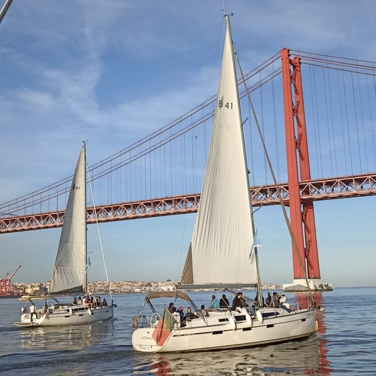 Sailboat cruising on the Tagus River with Lisbon's 25 de Abril Bridge in the background.
