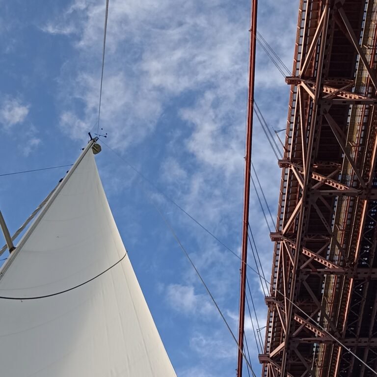 Close-up of a sailboat's mast and sails pointed towards the sky on the Tagus.