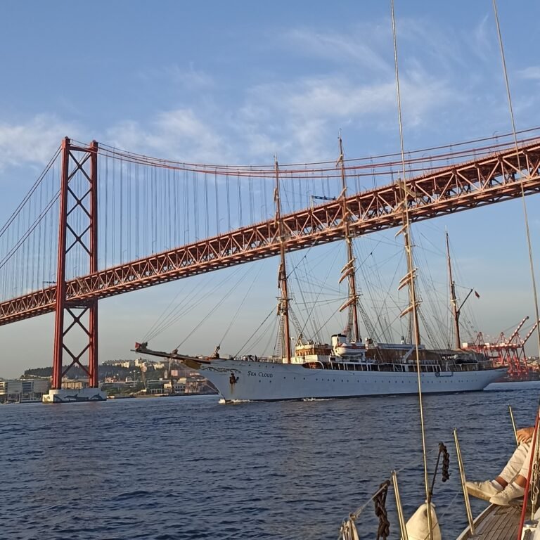 Sailboat on the Tagus River with the iconic 25 de Abril Bridge in the background.