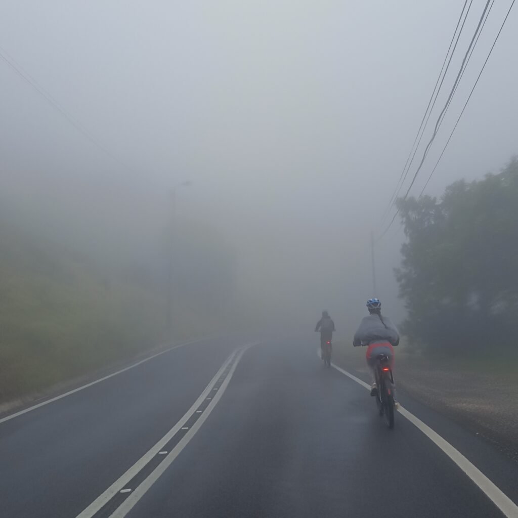 Riders pedaling through misty roads on the Cascais Bike Ride.