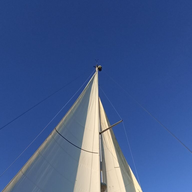 Large sailboat with a golden sail against the blue sky on the Tagus River.