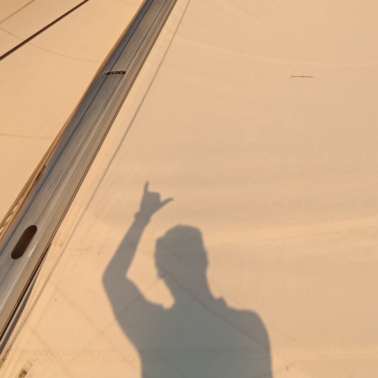 Shadow of a person taking a photo on the deck of a sailboat in Lisbon.