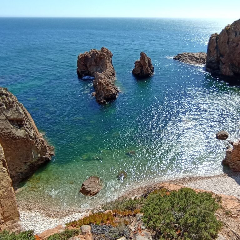 Rugged rock formations emerging from the clear blue Atlantic Ocean near Cascais.