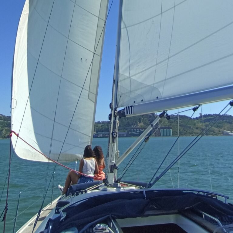 Two people relaxing on a sailboat deck, enjoying the Lisbon Brunch Sailing experience.