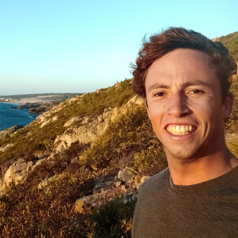 Portrait of an adventurer smiling with the Cascais coastal landscape in the background.