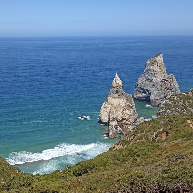 Expansive sandy beach with gentle waves and distant coastal cliffs in Cascais.