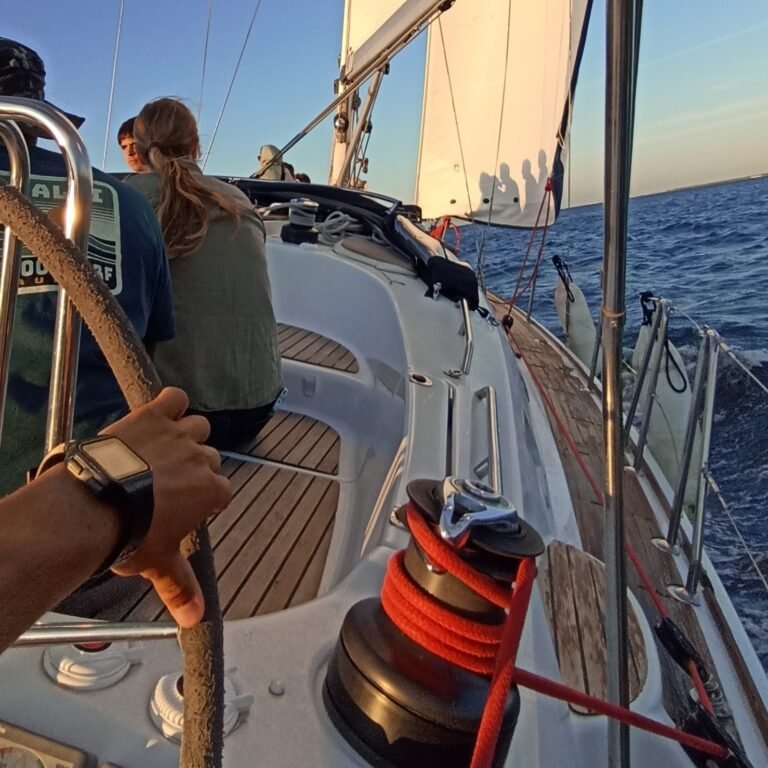 Sailboat cruising at sunset with the warm glow on the horizon over the Tagus River.