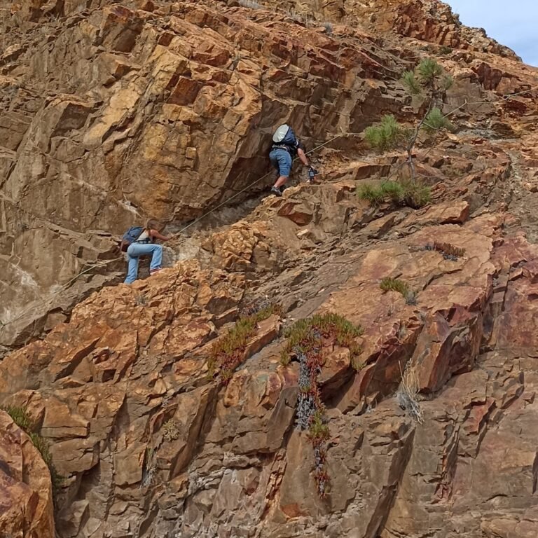 Hiker using ropes to ascend a steep rock section on the Atlantic Wild Hike.