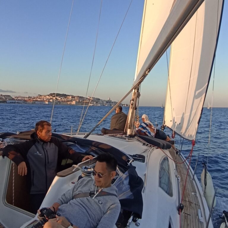 Sailboat on the Tagus River with Lisbon's city skyline in the distance.