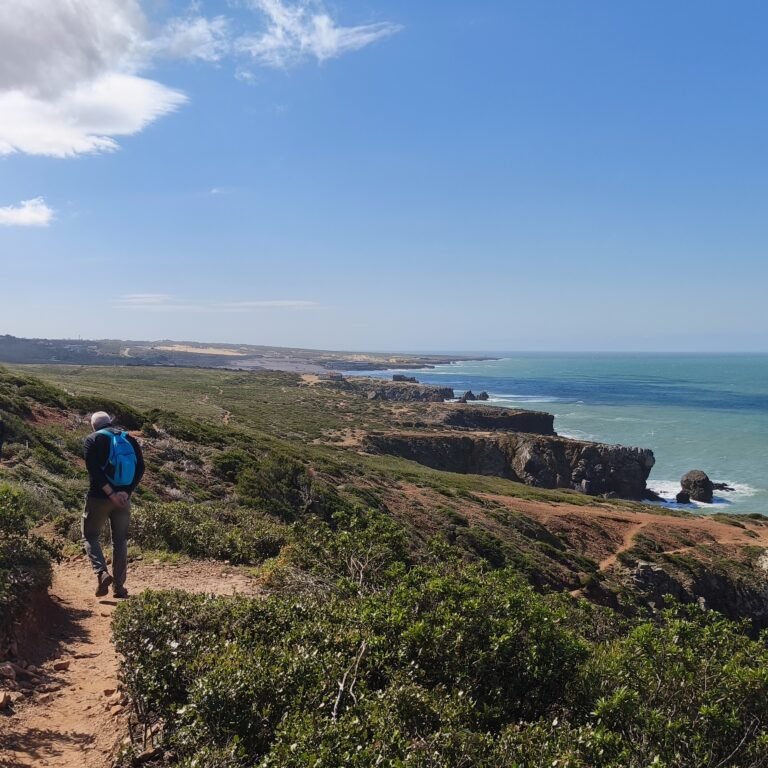 Hiker climbing coastal rocks during the Atlantic Wild Hike adventure.