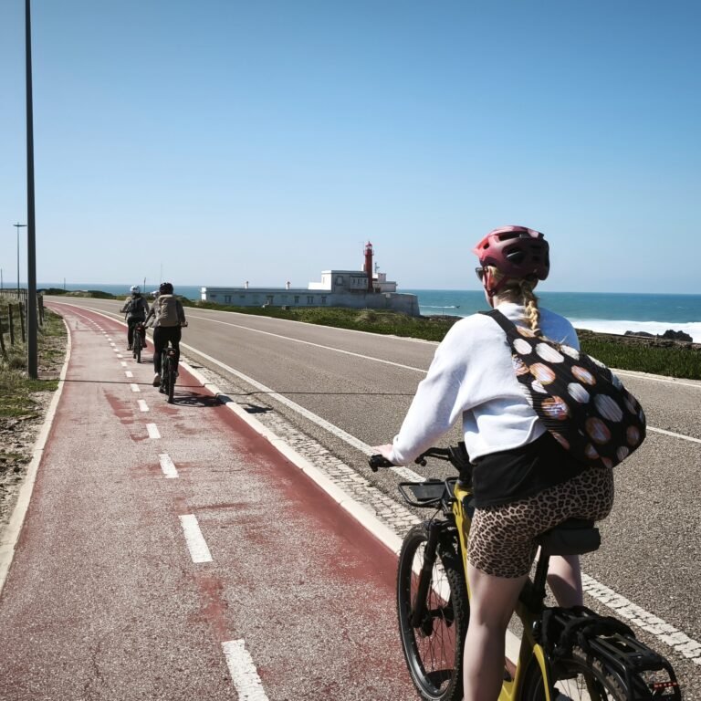 Solitary cyclist riding on a red bike path with a coastal view in Cascais.