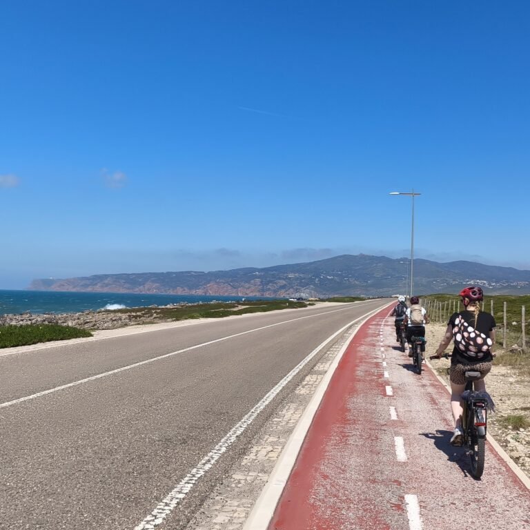People riding mountain bikes on a clear day in the Cascais landscape.