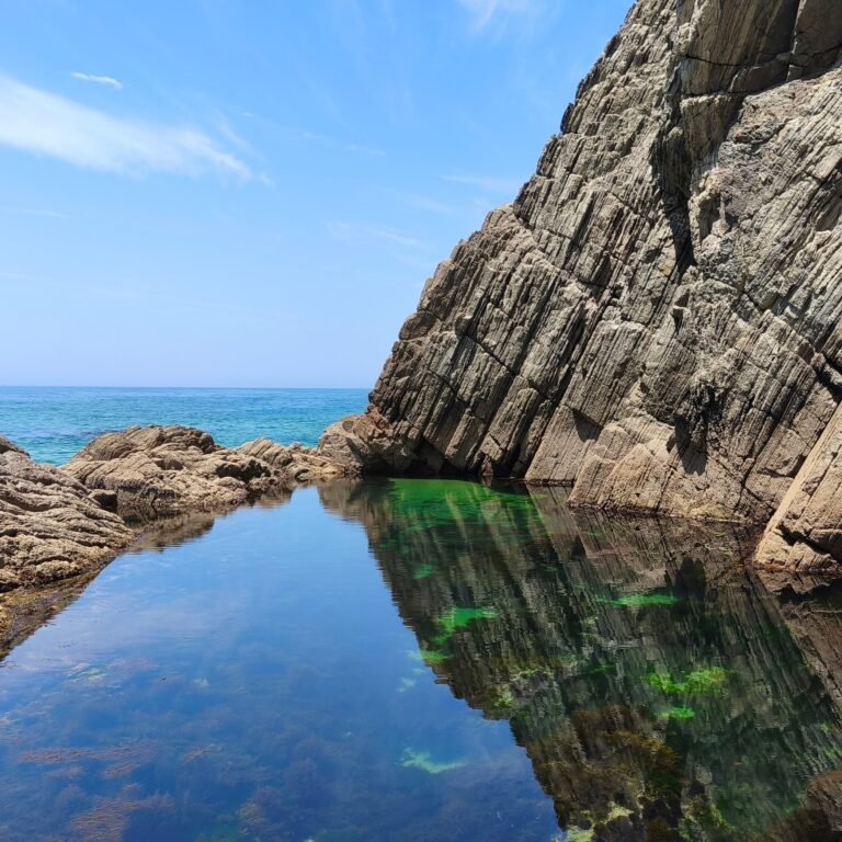 Dramatic sea cliffs and a natural rock pool on the Cascais coastline, Portugal.