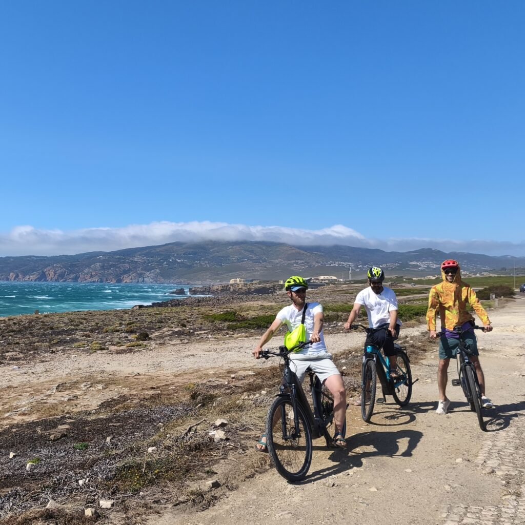 Bikers riding along the shoreline with views of the ocean on the Cascais Bike Ride.