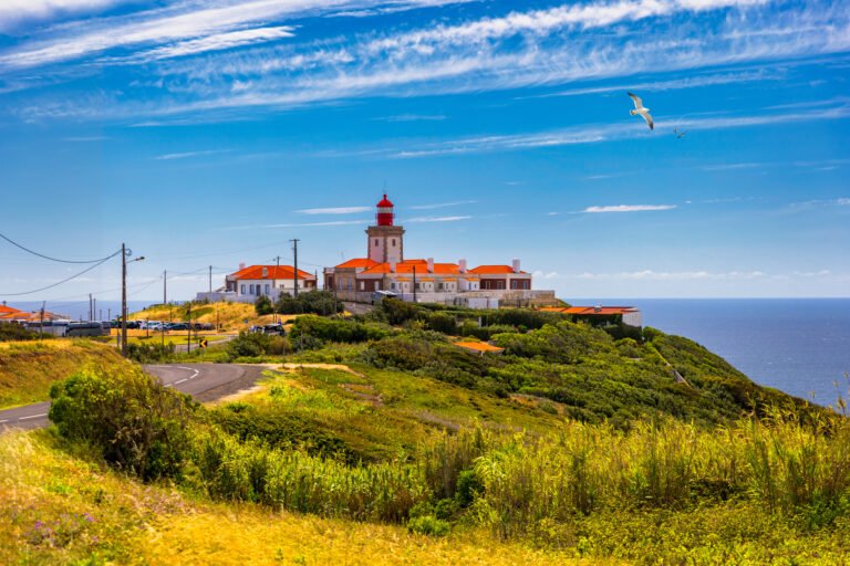 The lighthouse in Cabo da Roca. Cliffs and rocks on the Atlantic ocean coast in Sintra in a beautiful summer day, Portugal. Cabo da Roca, Portugal. Lighthouse and cliffs over Atlantic Ocean.