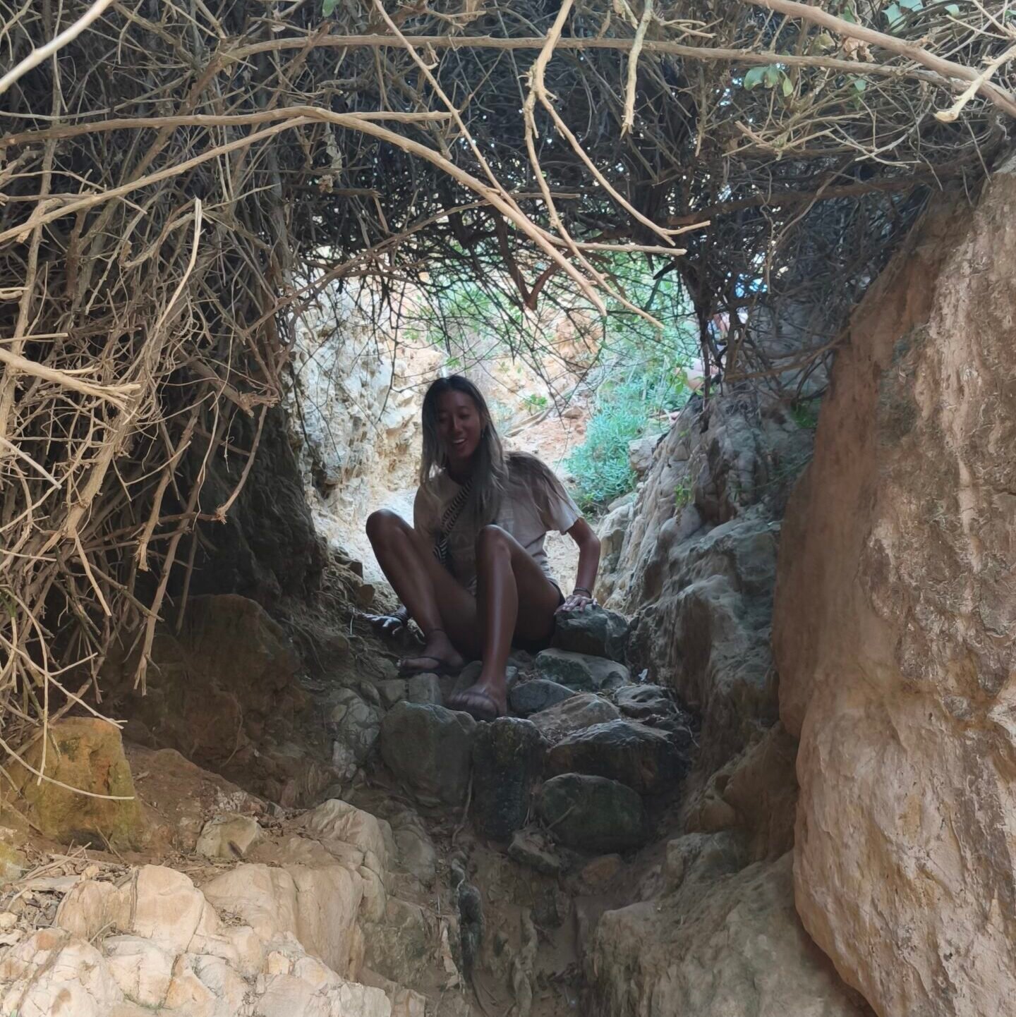 Tourist sitting inside a unique natural rock formation on the Cascais coast.