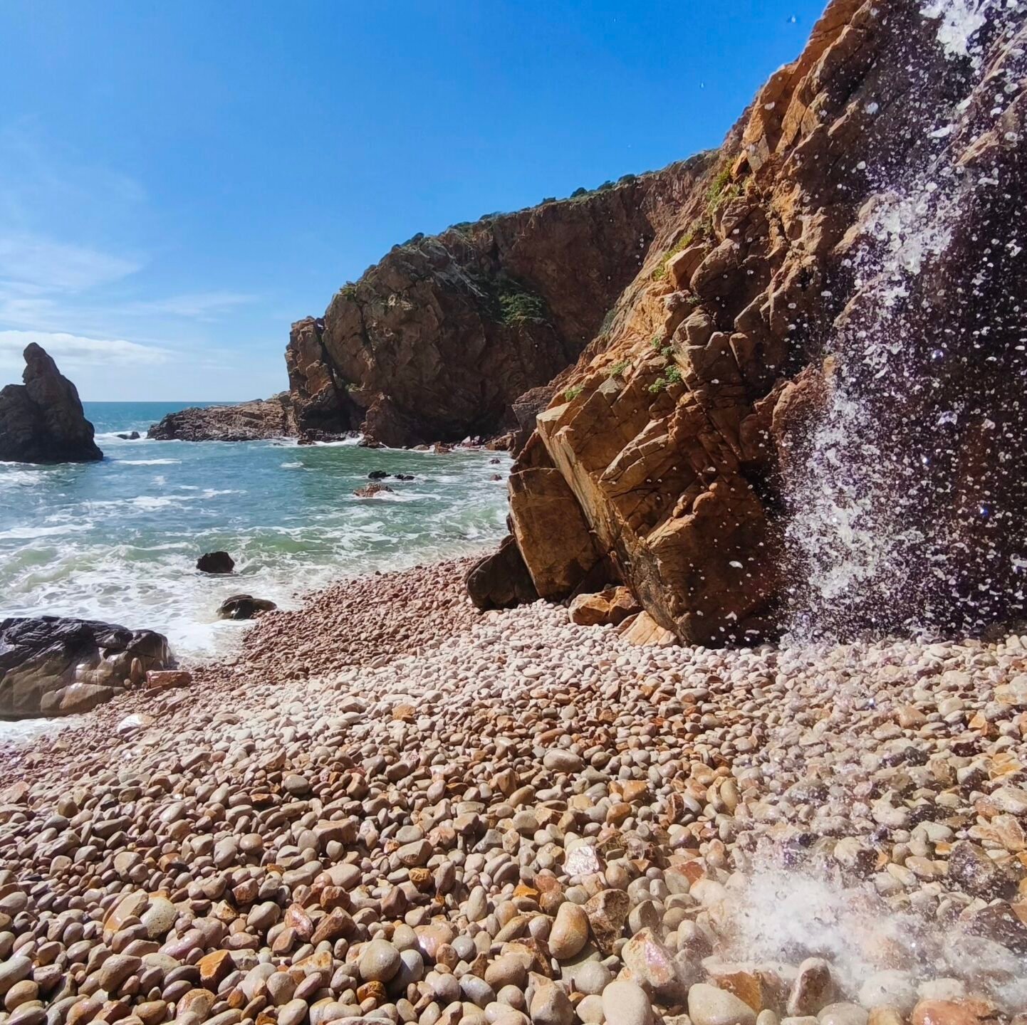 A secluded beach with a rocky shoreline and dramatic golden cliffs in Cascais.