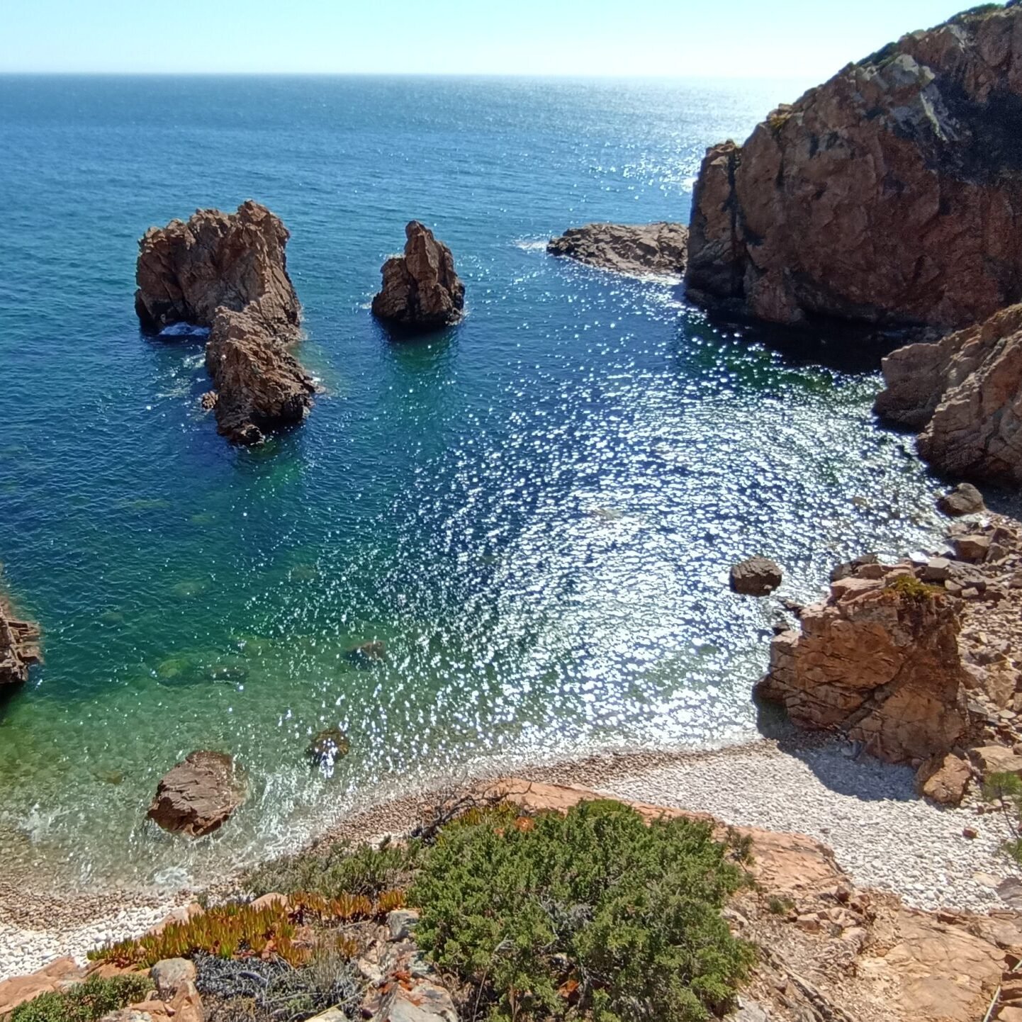High-angle view of a hidden coastal bay with transparent blue waters in Cascais, Portugal.
