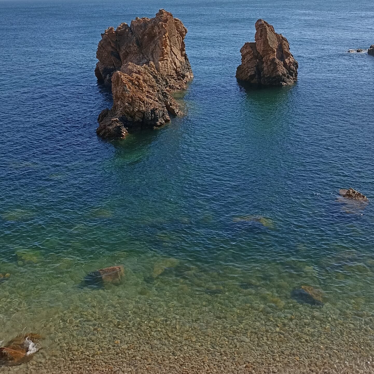Unique vertical rock formations emerging from the emerald green sea in Cascais.