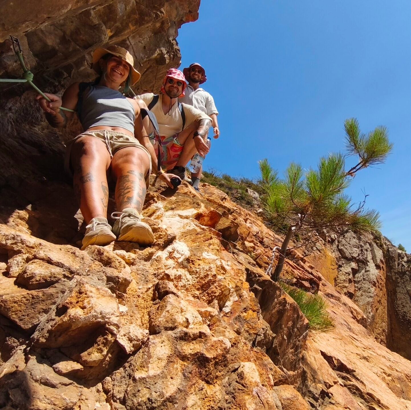 A group of tourists hiking up a rugged rocky slope with an adventure guide in Cascais.