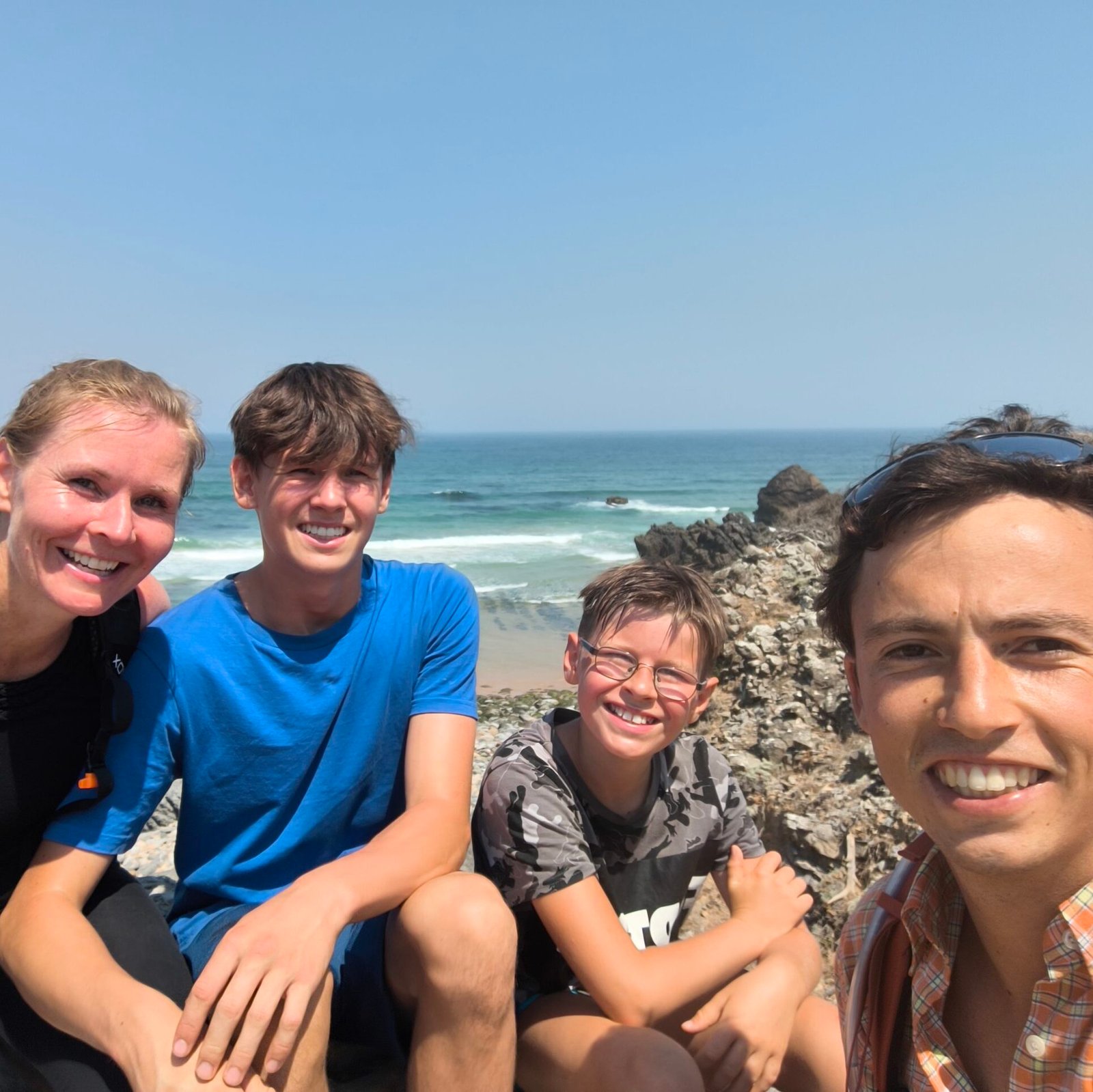 Group selfie of four young friends smiling during the Cascais Secret Beach & Cliff Jumping Private Tour.