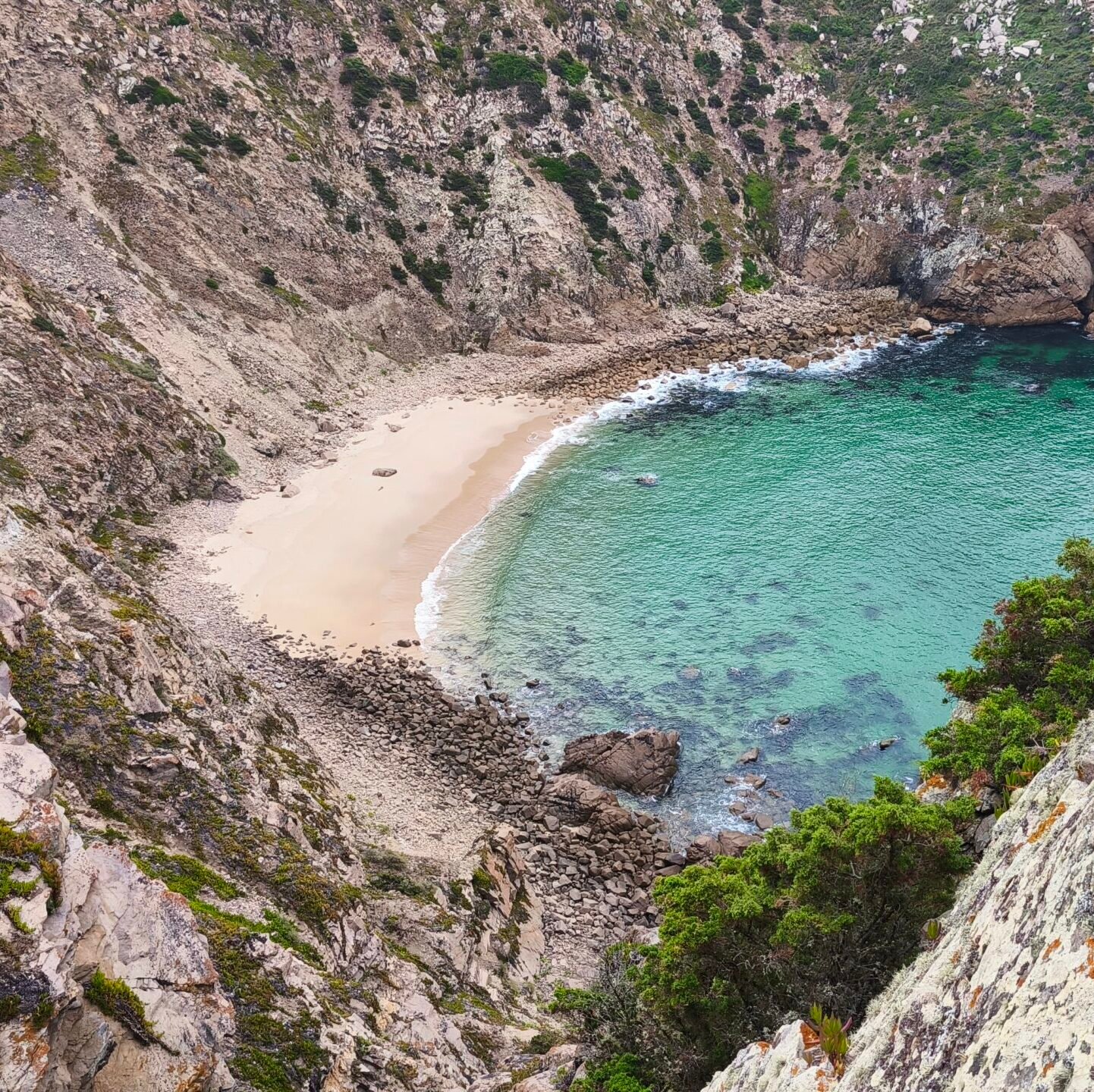 Spectacular aerial view of a hidden horseshoe-shaped beach with turquoise water in Cascais.