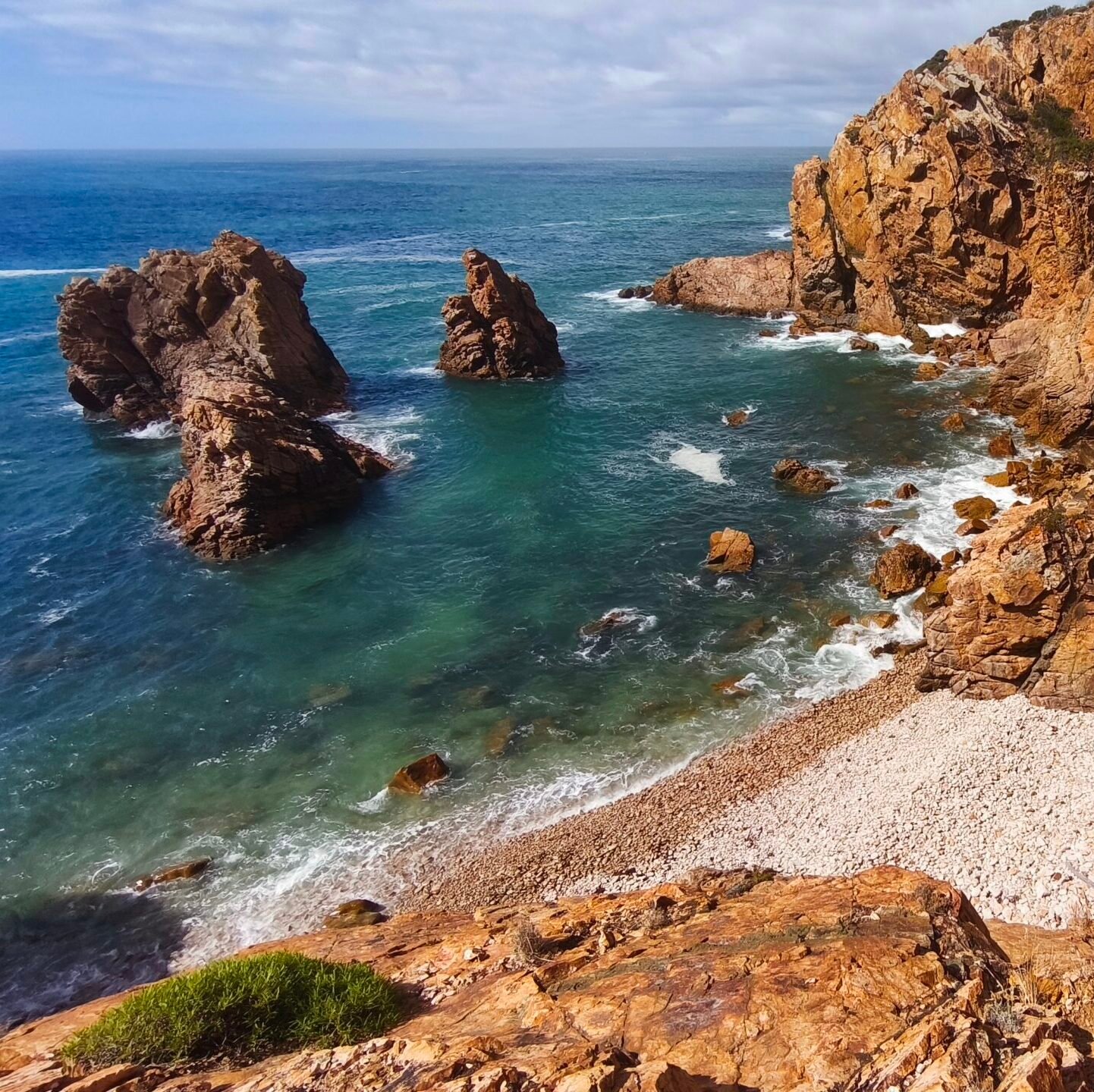 Imposing golden cliff faces meeting the deep blue ocean on the coast of Cascais.